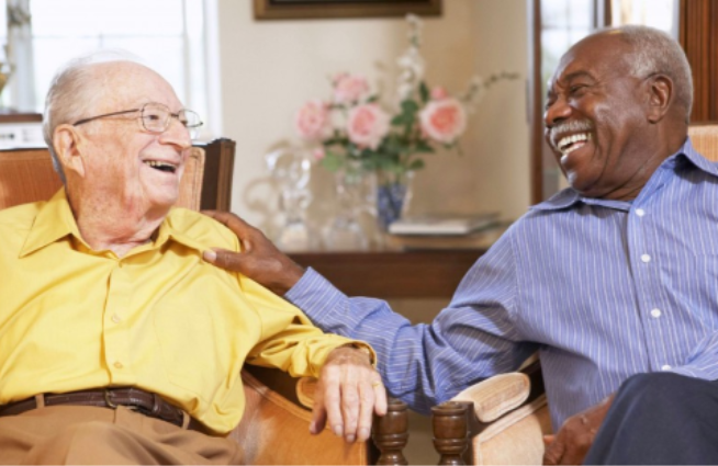 Photo of two elderly men sitting in chairs laughing